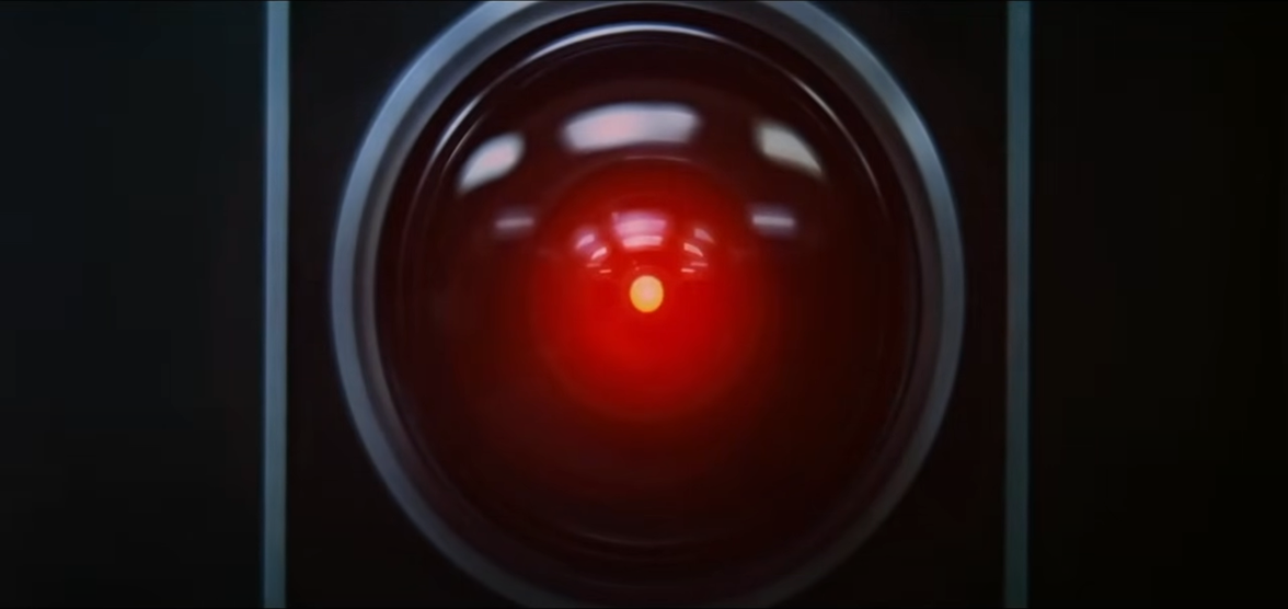 Close-up of HAL 9000's iconic red camera lens, reflecting red light.
